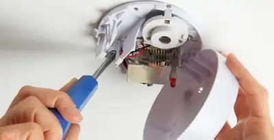 Certified technician wiring smoke detector during installation in Orlando, FL
